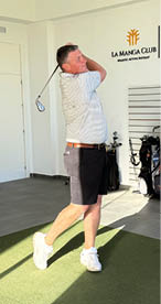 A man is swinging a golf club in a room with a green carpet. Description generated by AI