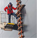 A man is on a ladder on a boat. Description generated by AI