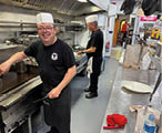 A man wearing a hat is cooking in a kitchen. Description generated by AI