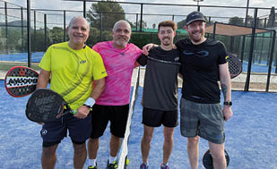 Four men standing on a tennis court. Description generated by AI