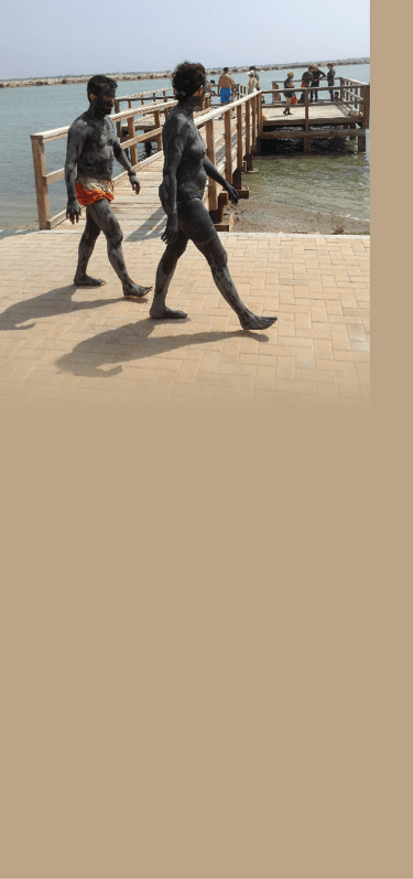 Two people walking on a sidewalk near the water. Description generated by AI