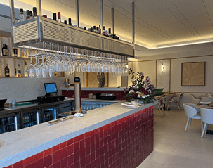 A bar with a red counter top and a large number of wine glasses. Description generated by AI