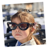 A young girl wearing sunglasses. Description generated by AI