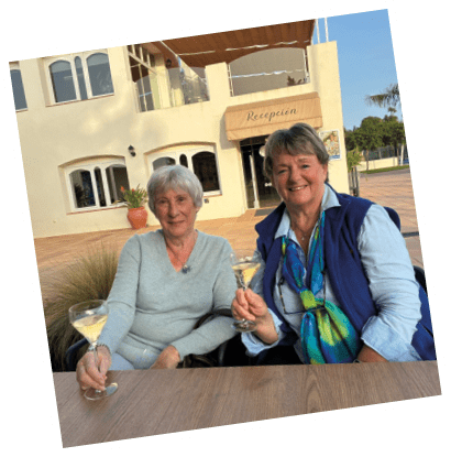 Two women sitting at a table with wine glasses. Description generated by AI