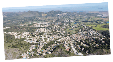 A view of a city from above with many buildings and a large body of water. Description generated by AI