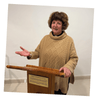A woman standing in front of a podium. Description generated by AI