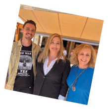 A man and two women are standing together under a tent. Description generated by AI
