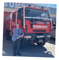 A man standing in front of a red truck with the word bombers on it. Description generated by AI