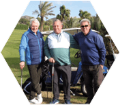 Three men standing on a golf course. Description generated by AI