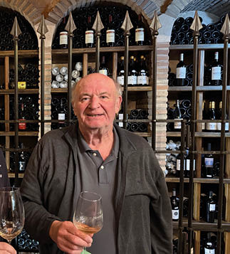 Two men standing in front of a wine cellar. Description generated by AI