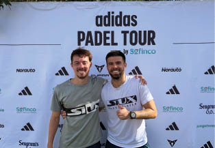 Two men posing in front of a white adidas banner. Description generated by AI