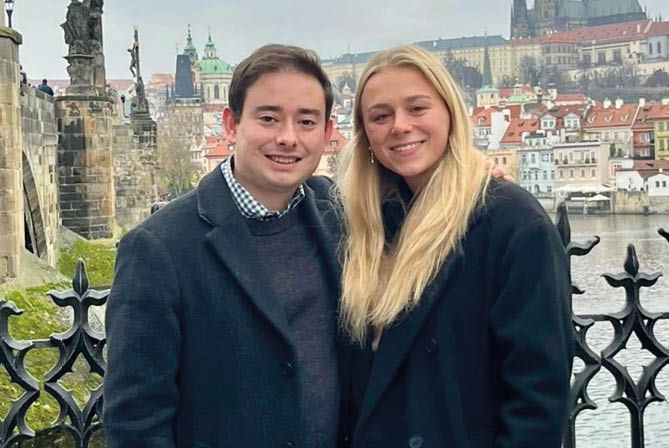 A man and woman standing on a bridge. Description generated by AI