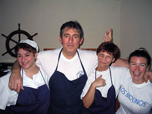 Four people wearing aprons and smiling. Description generated by AI