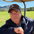 A man wearing a blue jacket is sitting in a golf cart. AI generated content