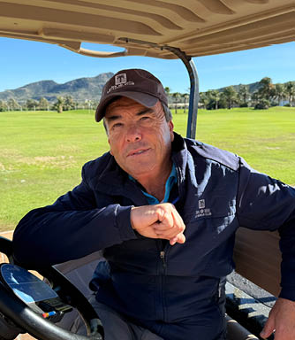 A man wearing a blue jacket is sitting in a golf cart. AI generated content