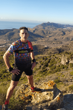 A man wearing a colorful shirt stands on a rocky hillside, posing for a picture. AI generated content
