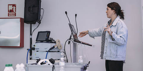 A woman standing in front of a laptop. Description generated by AI