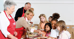 A group of people are gathered around a table with food. Description generated by AI