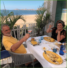 A man and woman are sitting at a table with food and drinks. Description generated by AI