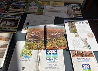A collection of brochures and pamphlets are laid out on a table. Description generated by AI