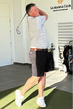 A man is swinging a golf club in a room with a green carpet. Description generated by AI