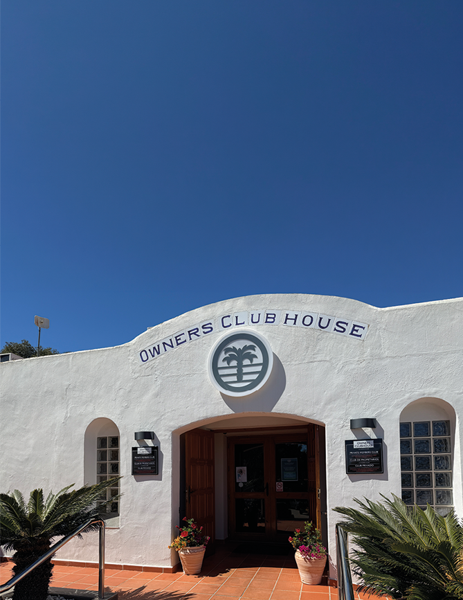 A white building with a blue sign that says Owner's Clubhouse. Description generated by AI