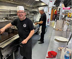 A man wearing a hat is cooking in a kitchen. Description generated by AI