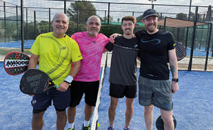 Four men standing on a tennis court. Description generated by AI
