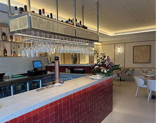 A bar with a red counter top and a large number of wine glasses. Description generated by AI