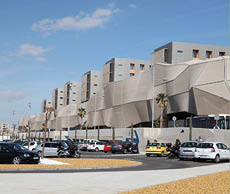 A parking lot with many cars parked in front of a building. Description generated by AI