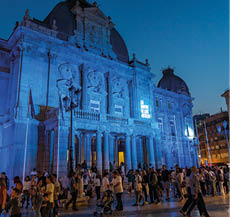 A large crowd of people are gathered outside of a building at night. Description generated by AI