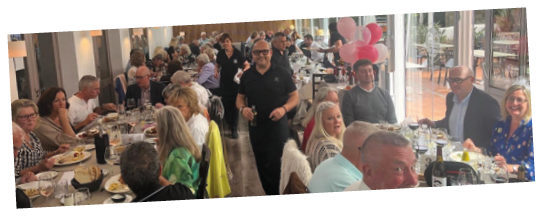 A group of people are sitting at a table in a restaurant. Description generated by AI