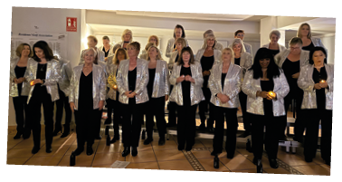 A group of women wearing silver jackets and black pants. Description generated by AI