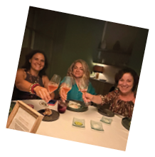 Three women sitting at a table with wine glasses. Description generated by AI