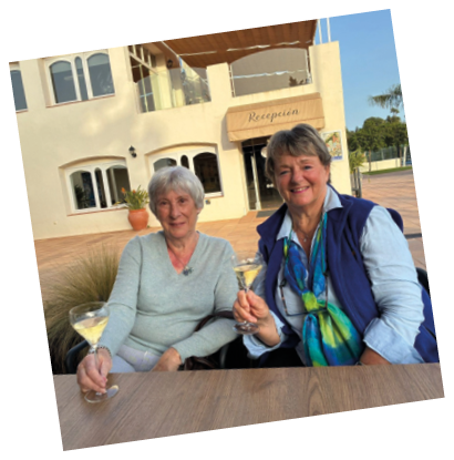 Two women sitting at a table with wine glasses. Description generated by AI