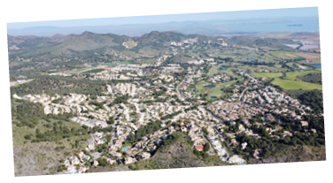 A view of a city from above with many buildings and a large body of water. Description generated by AI
