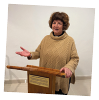 A woman standing in front of a podium. Description generated by AI