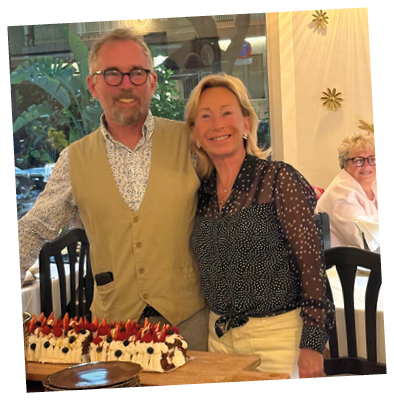 A man and woman standing in front of a table with a cake on it. Description generated by AI