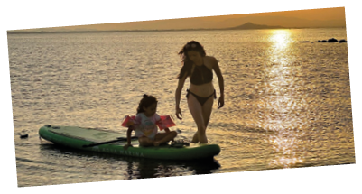 A woman and a child are on a green surfboard in the water. Description generated by AI
