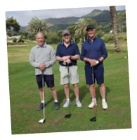 Four men standing on a golf course. Description generated by AI