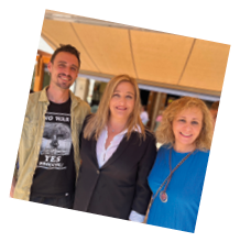 A man and two women are standing together under a tent. Description generated by AI