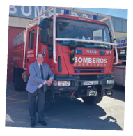 A man standing in front of a red truck with the word bombers on it. Description generated by AI