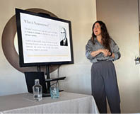 A woman is standing in front of a TV screen. Description generated by AI