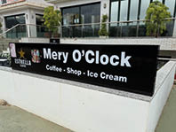 A black sign with white letters that says “Mery O'Clock" on it. Description generated by AI