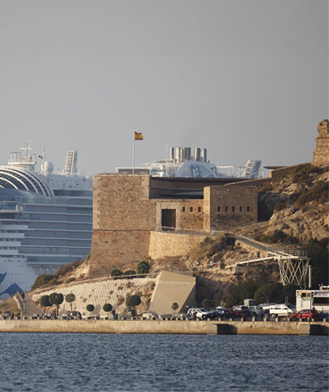 A large blue and white cruise ship is docked at a pier. Description generated by AI
