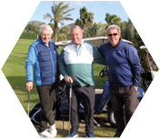 Three men standing on a golf course. Description generated by AI