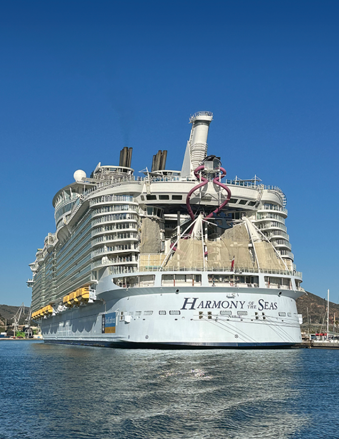 A large cruise ship with a yellow bow. Description generated by AI