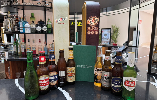 A variety of beer bottles are displayed on a table. Description generated by AI