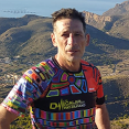 A man wearing a colorful shirt stands on a rocky hillside, posing for a picture. AI generated content