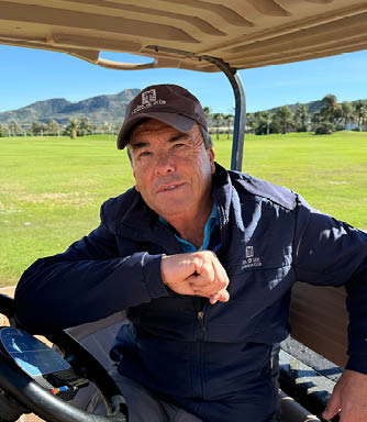 A man wearing a blue jacket is sitting in a golf cart. AI generated content